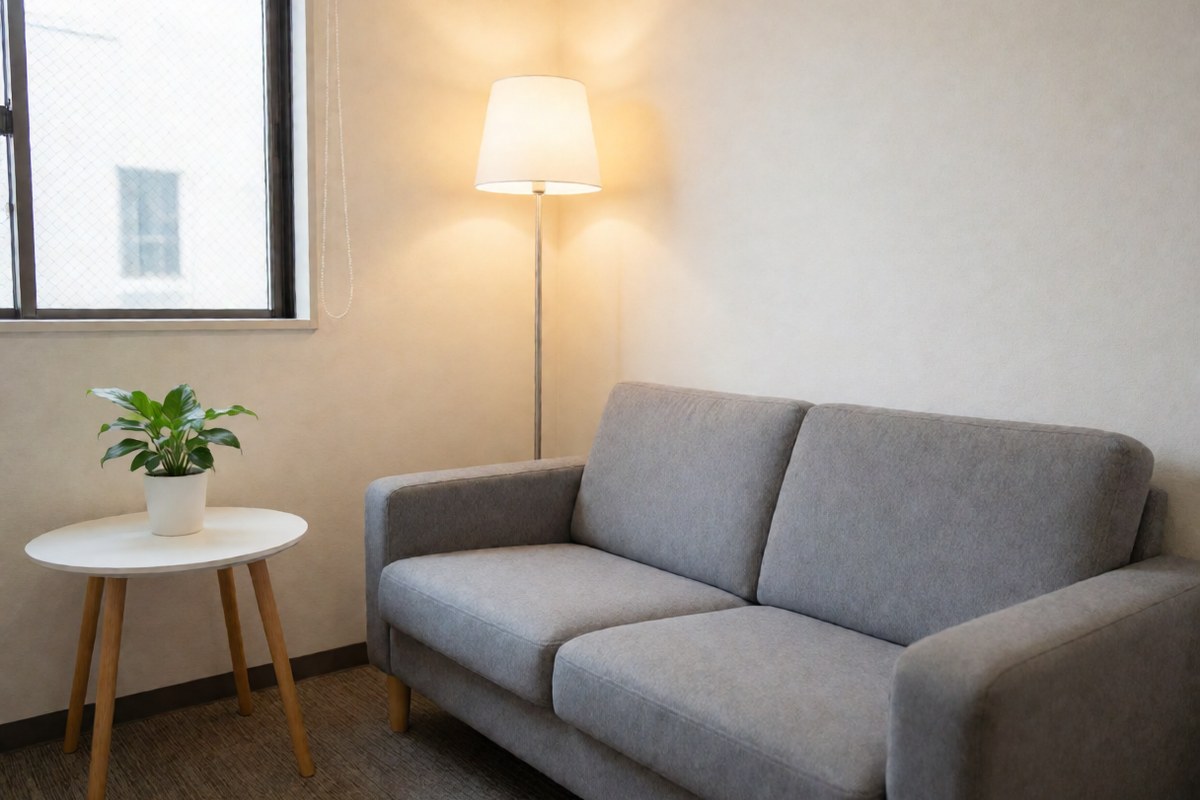 Small, quiet waiting room with a sofa, a lamp and a rack of reading material